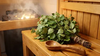 Detail whisk daun dan gayung kayu di bangku sauna